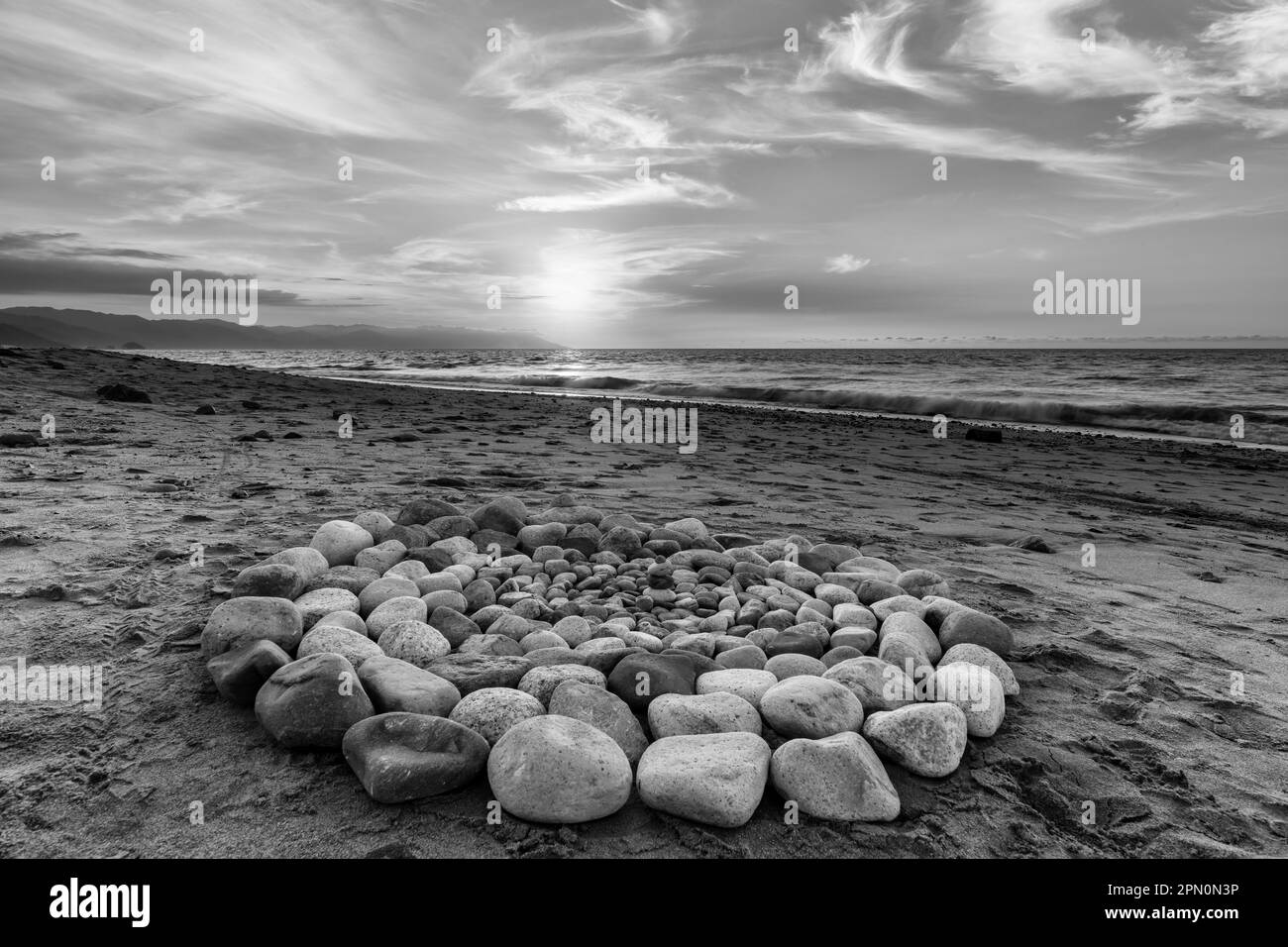 Le pietre rituali sacre per la cerimonia spirituale sono organizzate in un cerchio durante il tramonto sulla spiaggia Foto Stock