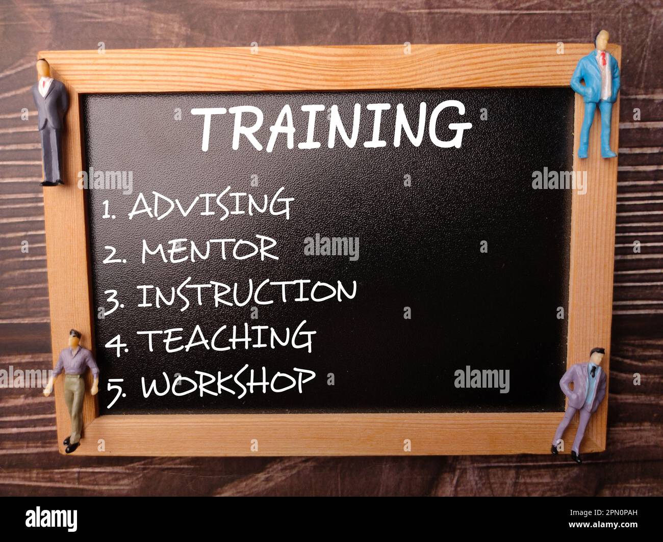 Tavole di legno e persone in miniatura con concetto di formazione parola su uno sfondo di legno Foto Stock