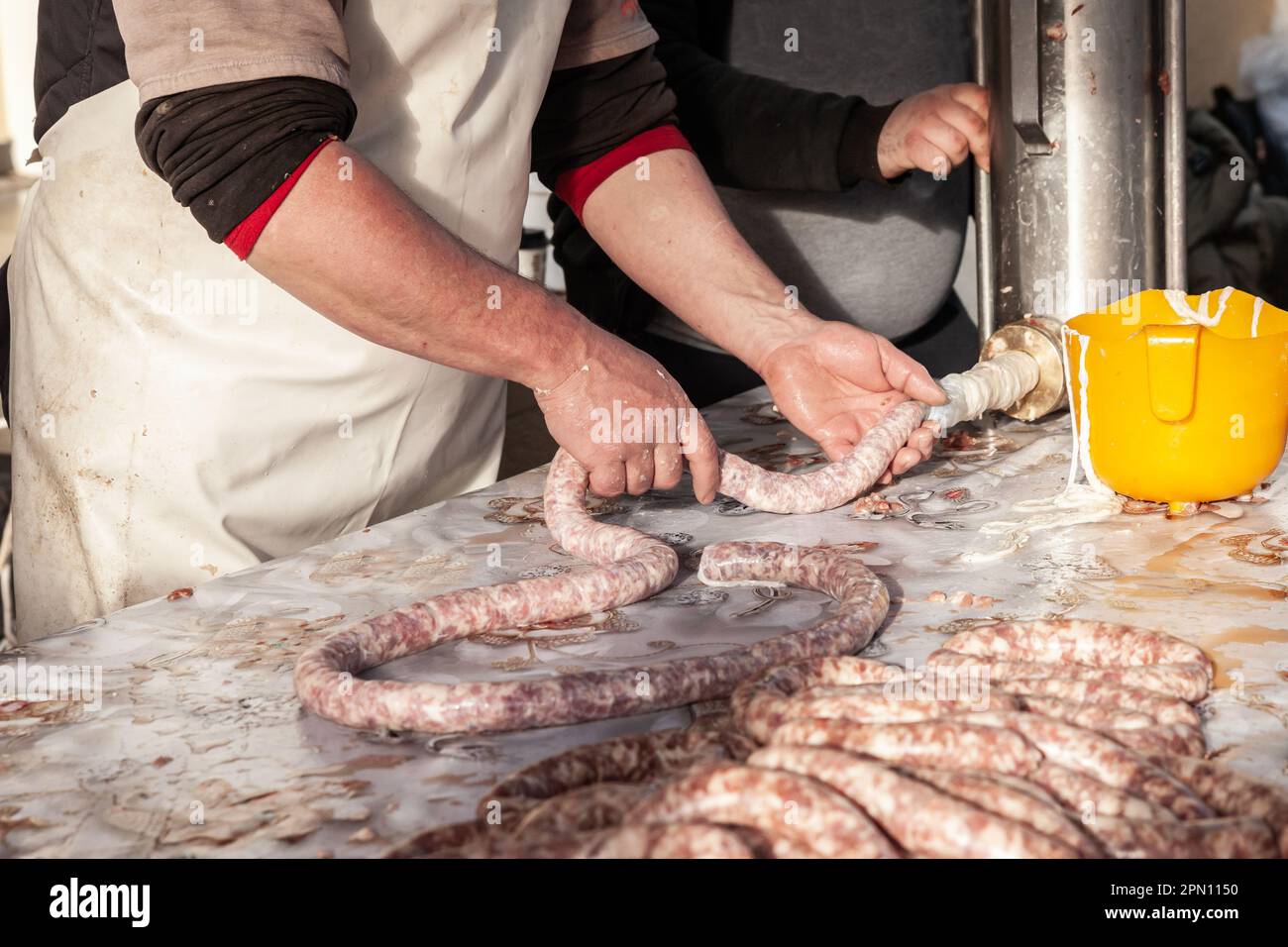 Foto di persone in Serbia che preparano la salsiccia manualmente, con un macinacaffè, una macchina per salsiccia, specializzata nella preparazione e lavorazione della carne in salsiccia. Foto Stock