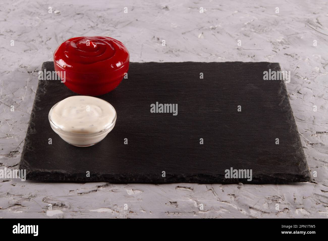 Salse da immersione rosse e bianche su tavola da servizio in ardesia nera con spazio vuoto. Salsa celeste armonia. Foto Stock