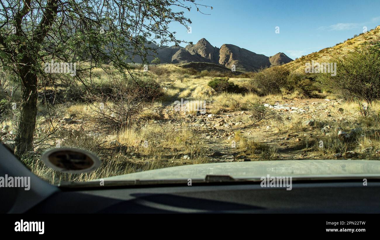 Una pista di montagna attraverso un letto di fiume asciutto, sparato attraverso il parabrezza di un 4x4, mostrando cofano e disco delle tasse. Foto Stock