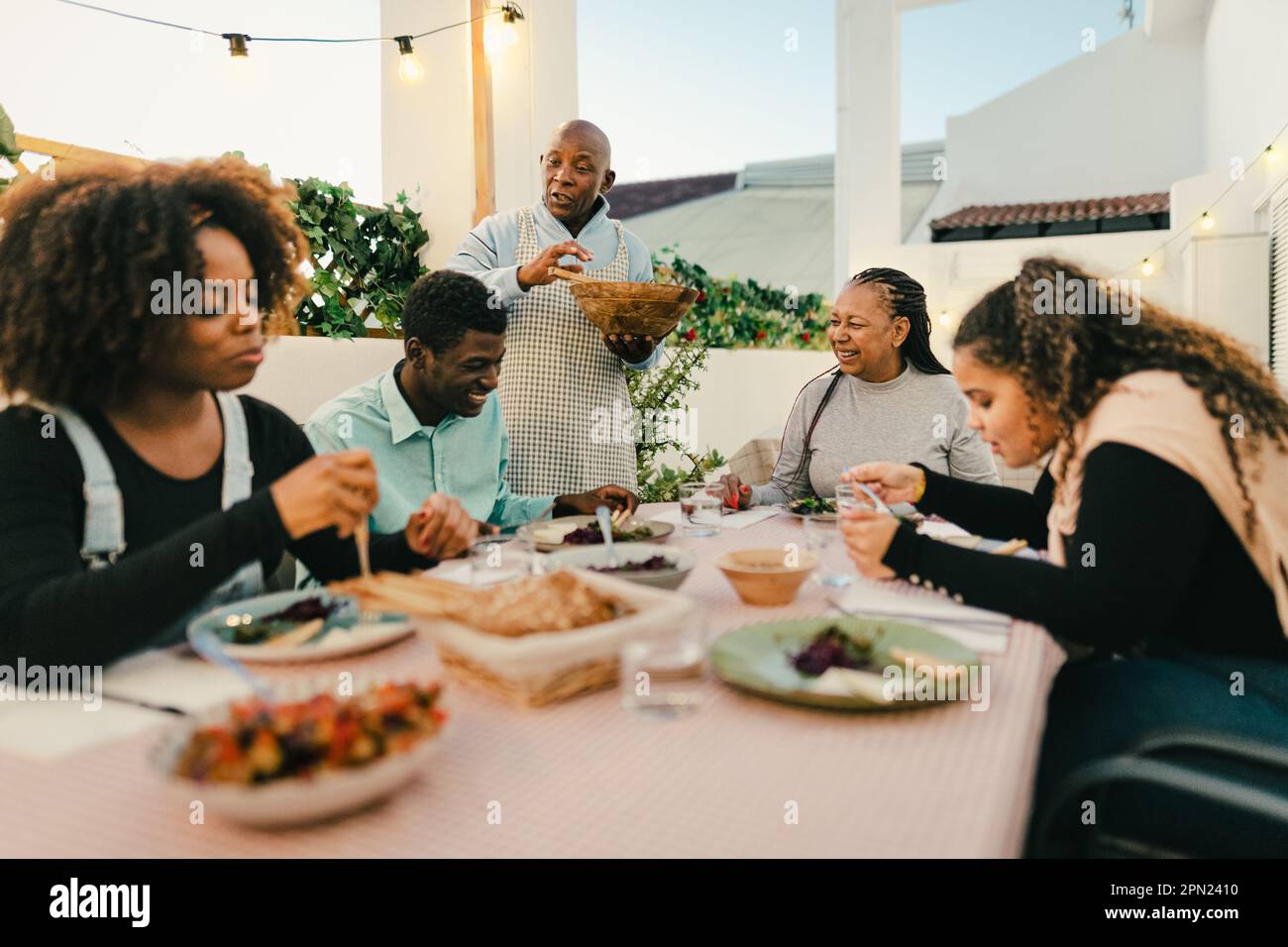 Felice famiglia africana che cena insieme sul patio della casa - concetto di riunione della famiglia Foto Stock