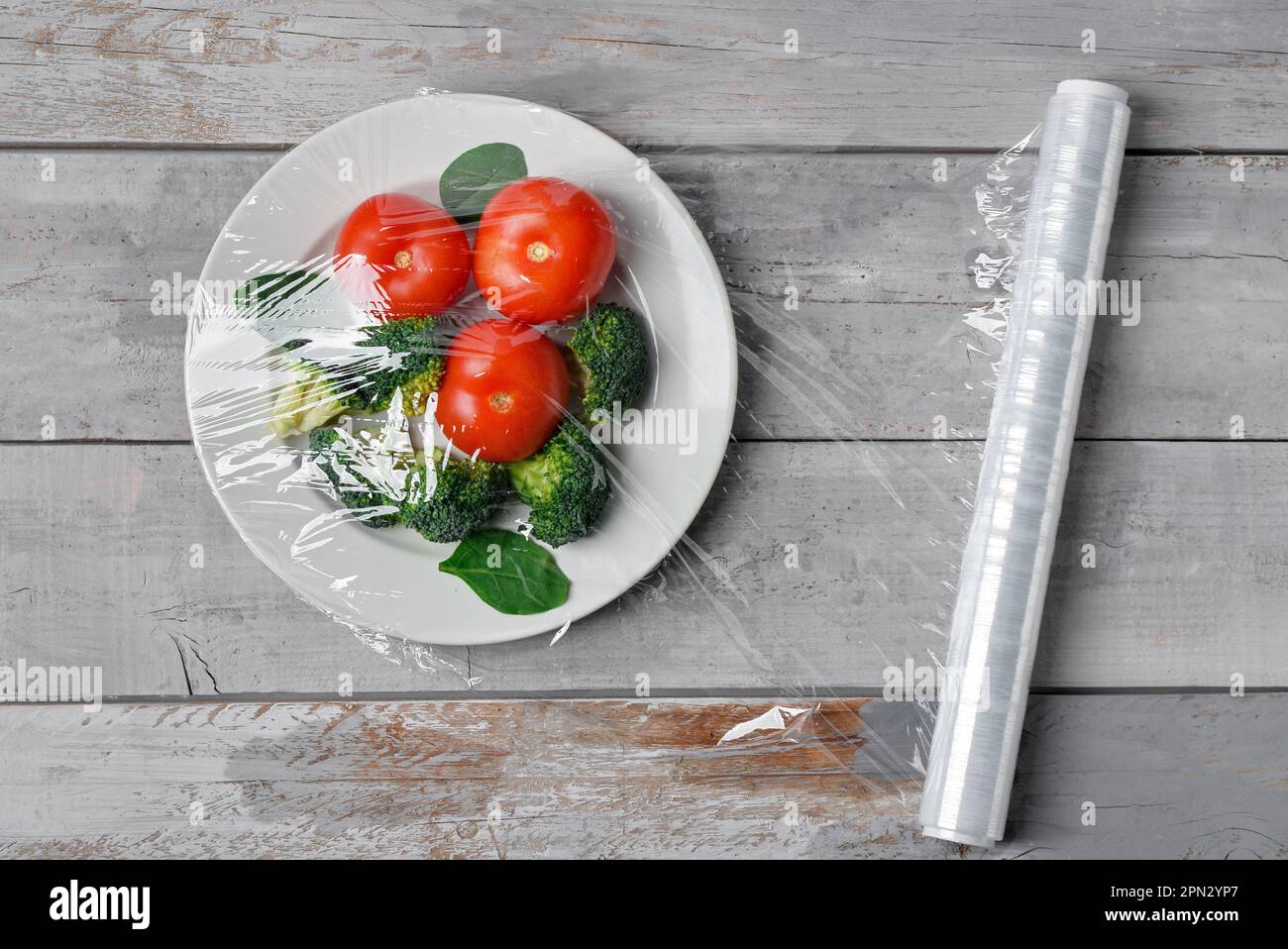 Piatto con verdure avvolto con fascia elastica su fondo grigio in legno Foto Stock