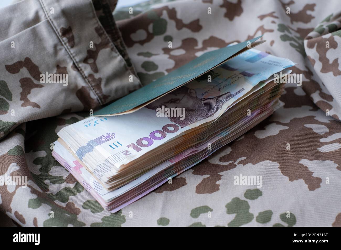 Carta d'identità militare Ucraina e hryvnia su uniforme militare. Pagamenti ai soldati dell'esercito ucraino, stipendi ai militari. Guerra in Ucraina Foto Stock