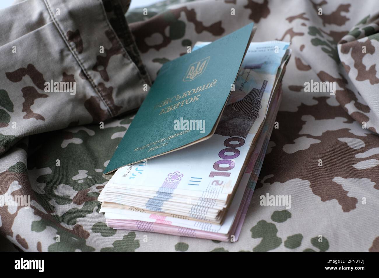 Carta d'identità militare Ucraina e hryvnia su uniforme militare. Pagamenti ai soldati dell'esercito ucraino, stipendi ai militari. Guerra in Ucraina Foto Stock