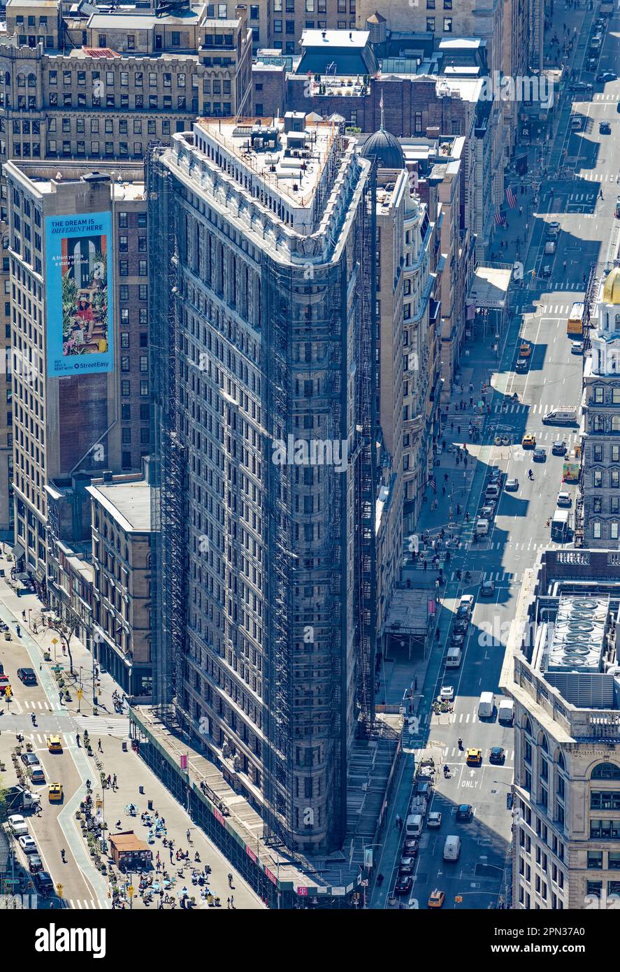 Flatiron Building, un'icona di New York, vista attraverso la foschia di un'altra icona, l'Empire state Building. I ponteggi ristrutturati oscurano la facciata. Foto Stock