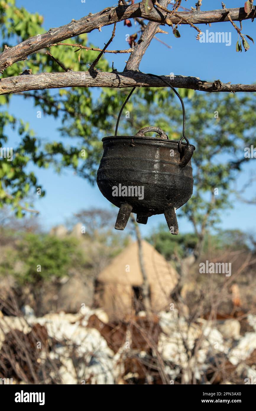 Una potje nera a tre zampe, o pentola da cucina, appesa ad un ramo in un villaggio di Himba in Namibia. Foto Stock