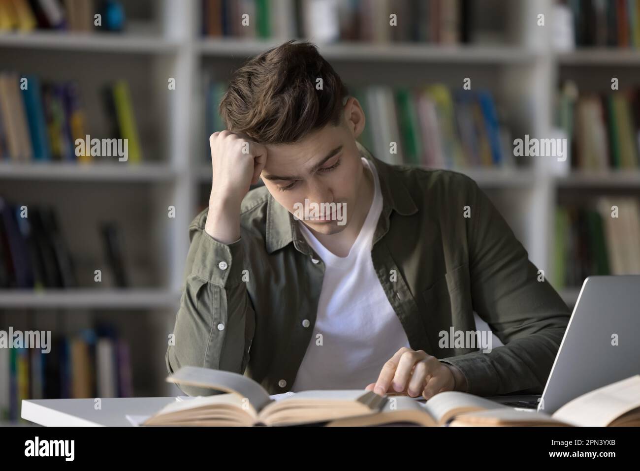 Studente che studia in biblioteca si sente annoiato o stanco Foto Stock