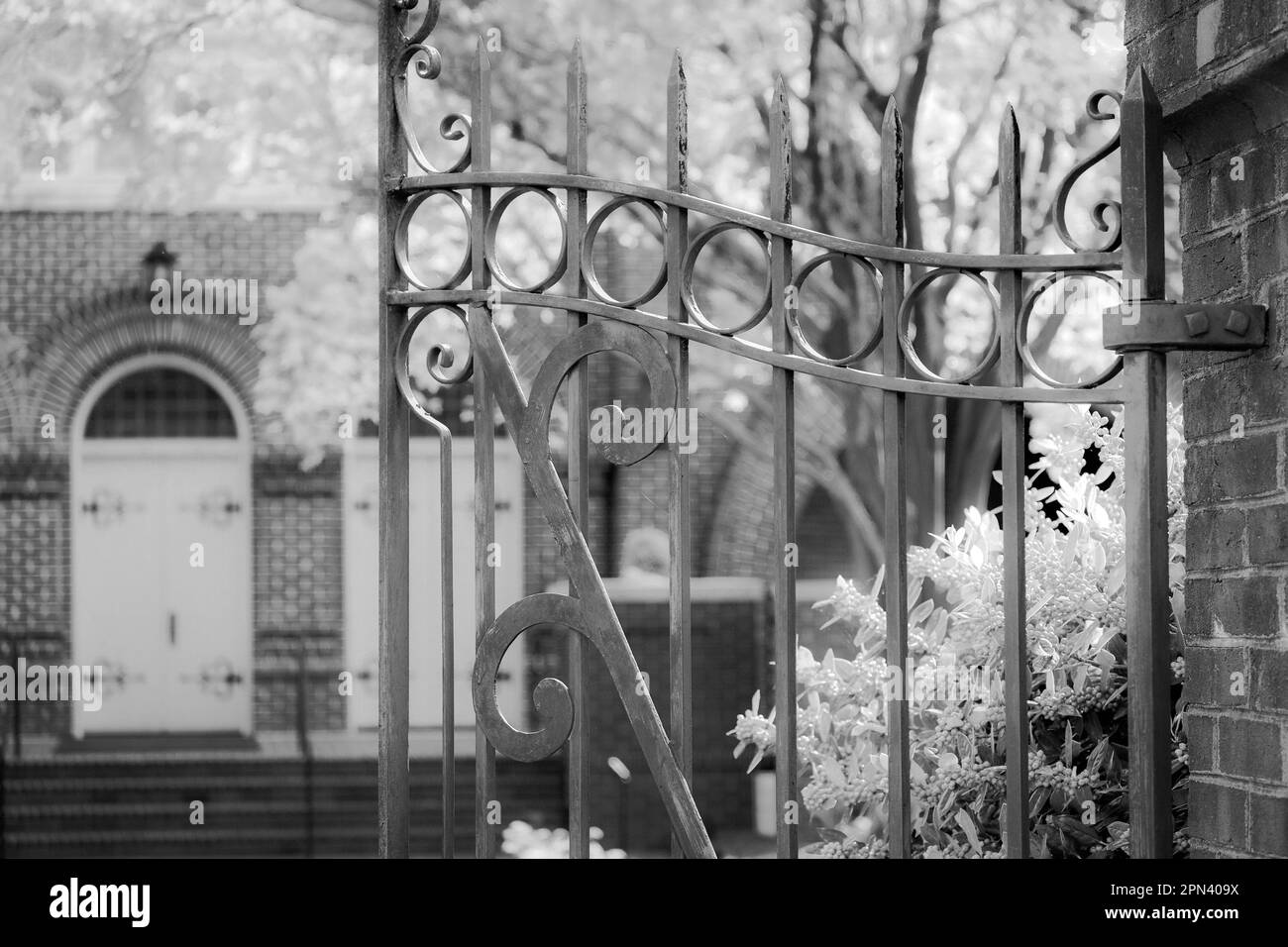 Cancello in ferro battuto aperto e invitando nel giardino della chiesa. Foto Stock Cancello in ferro battuto aperto e invitando nel giardino della chiesa. Foto Stock