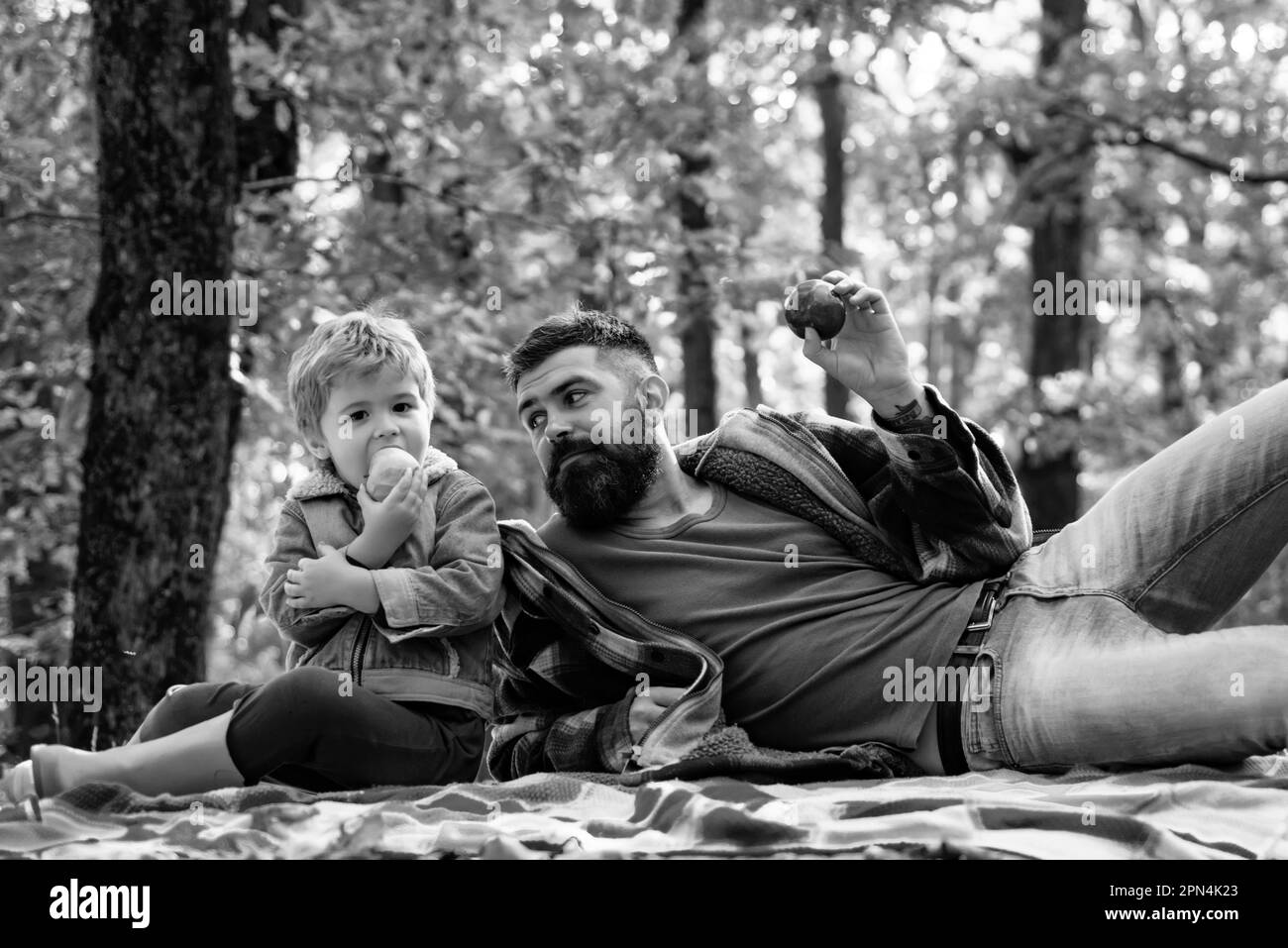 Snack sano. Mordere la mela succosa. Picnic per famiglie. Hipster sopportato papà con figlio passare il tempo nella foresta. Brutale uomo barbuto e ragazzo mangiano mele Foto Stock