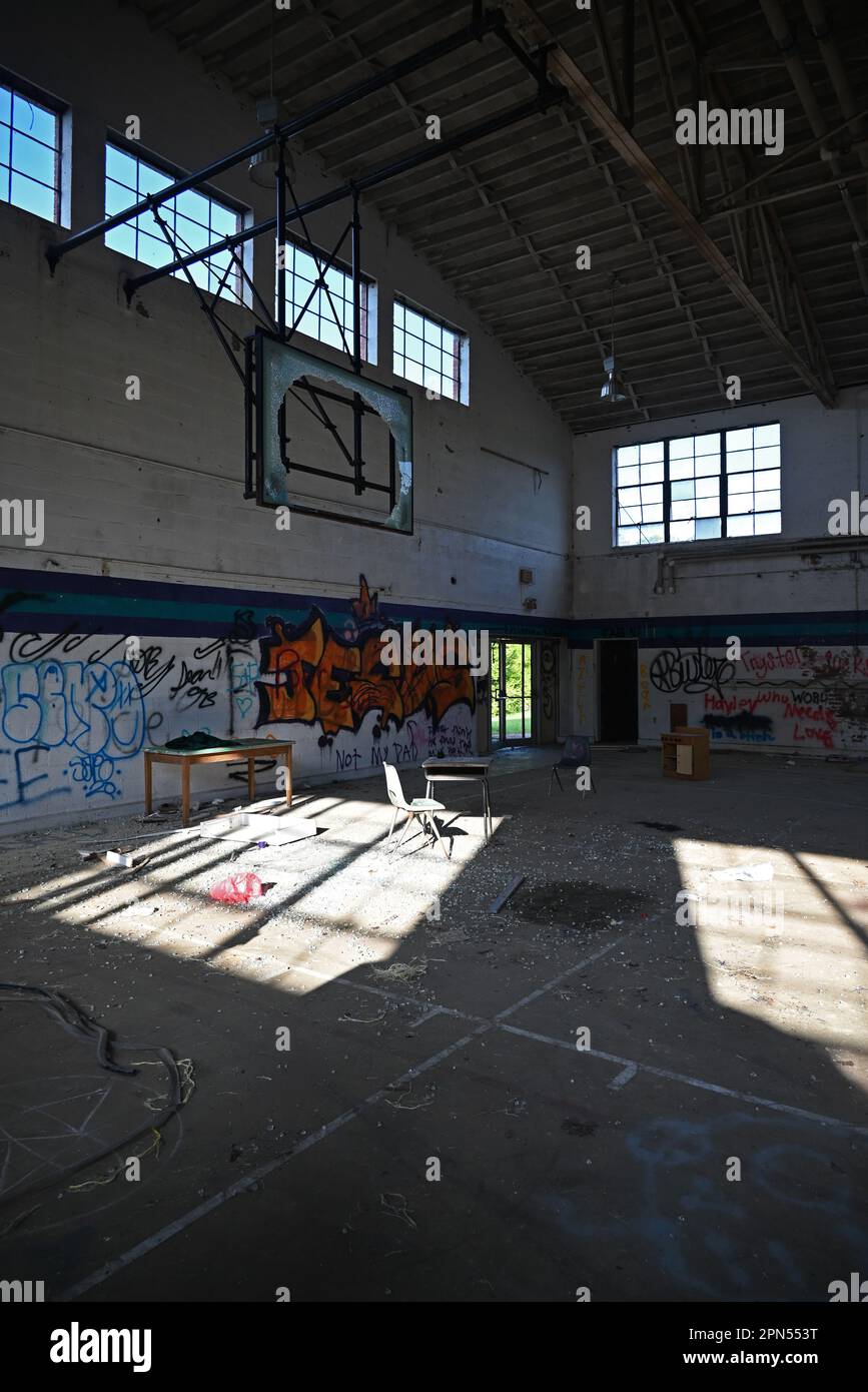 Una palestra piena di graffiti e detriti in una scuola abbandonata dal 2001. Foto Stock