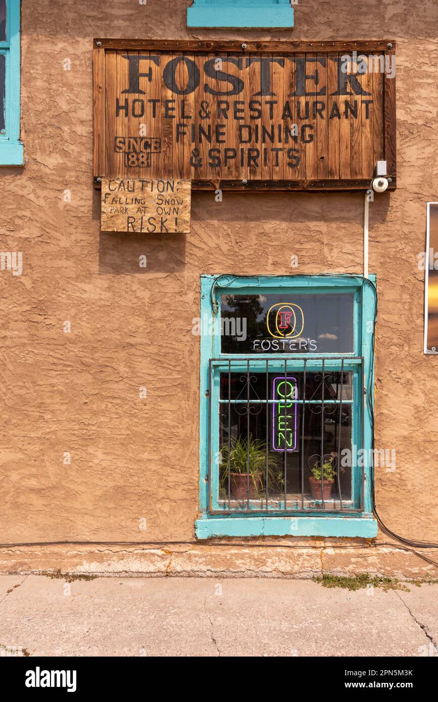 Esterno beige parete adobe con cornice turchese finestra e segno per Foster Hotel & Restaurant, costruito intorno al 1881, a Chama, New Mexico, Stati Uniti. Foto Stock