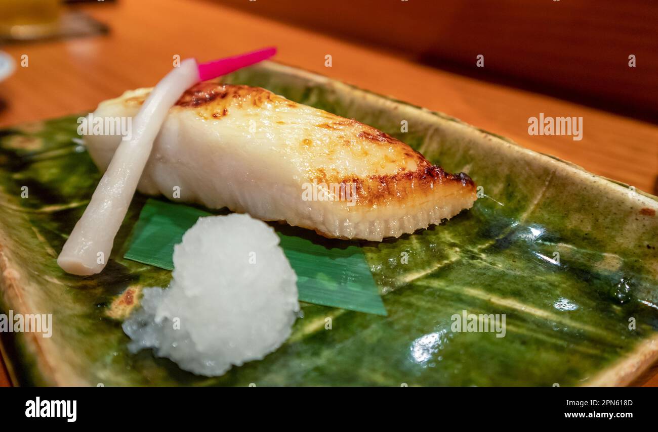 Pesce alla griglia caldo isolato su una piastra di ceramica verde. Piatto giapponese. Foto Stock