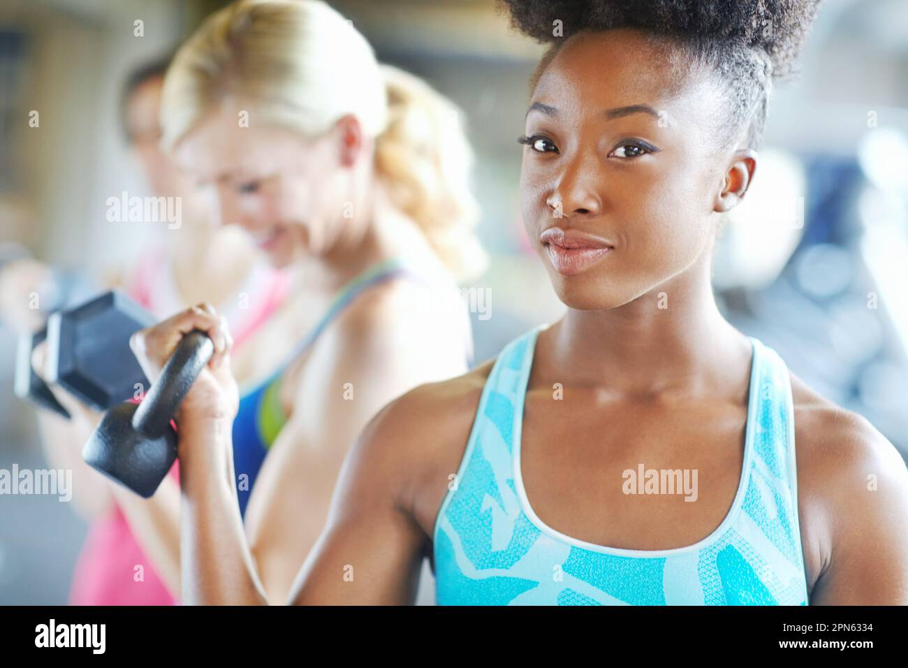 Questa cosa è più leggera della mia borsa. una giovane donna attraente che tiene un manubrio in palestra. Foto Stock Questa cosa è più leggera della mia borsa. una giovane donna attraente che tiene un manubrio in palestra. Foto Stock