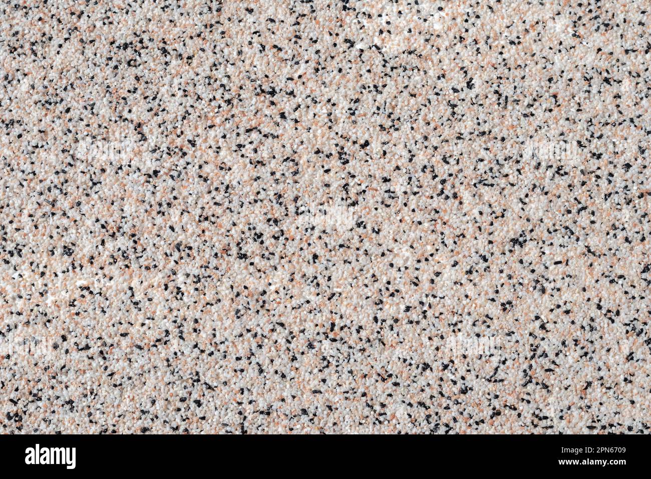 Vista dall'alto del piano cottura sgranato. Superficie di tavola vuota macchiata, fondo astratto con piccole pietre bianche e nere, materiale grezzo, luce granata Foto Stock