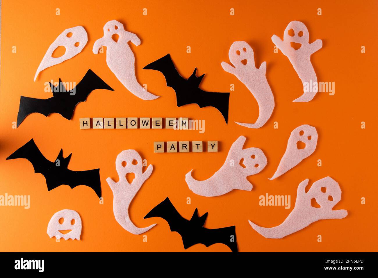 Fantasmi bianchi e mazza per la festa di Halloween. Immagine fantasma della carta di avvolgimento su sfondo arancione vista dall'alto. Fumetto Creepy Whisper. Fai-da-te fatto a mano. Impostare i caratteri boo. Parola frase di legno della lettera. Foto Stock
