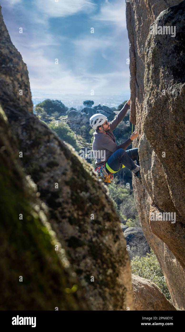Giovane adulto che si arrampica su una gola di granito a Torrelodones, Madrid. Arrampicata su roccia. Concetto di sport estremi Foto Stock