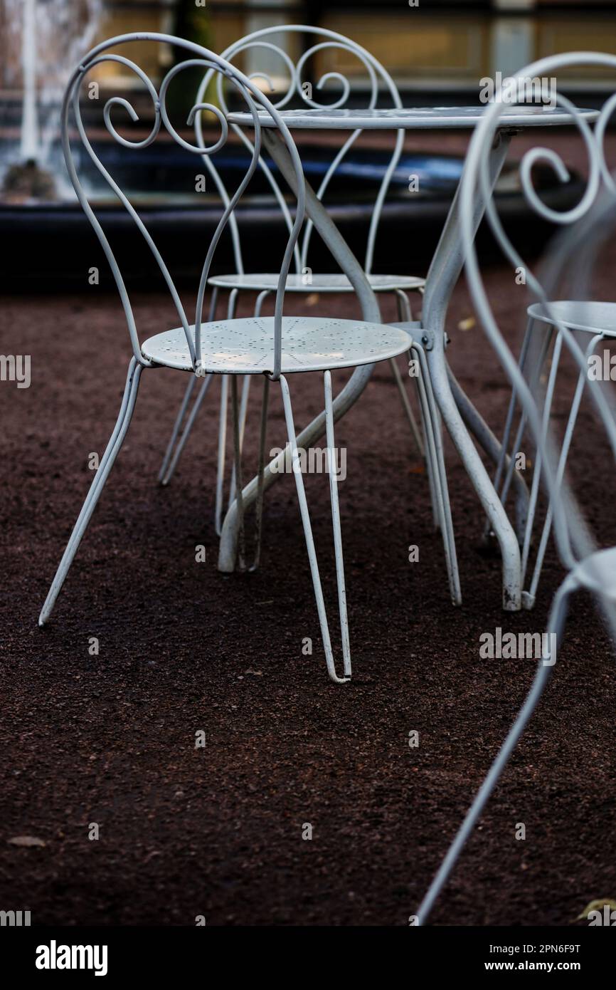 Sedie bianche e tavoli vuoti in metallo in stile vittoriano nel cafe' all'aperto. Mobili in ferro battuto, vecchia moda accogliente caffetteria terrazza, Foto Stock