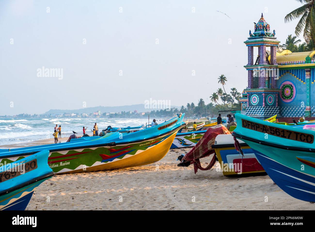 Barche da pesca e un tempio sulla costa orientale dello Sri Lanka vicino a Trincomalee Foto Stock
