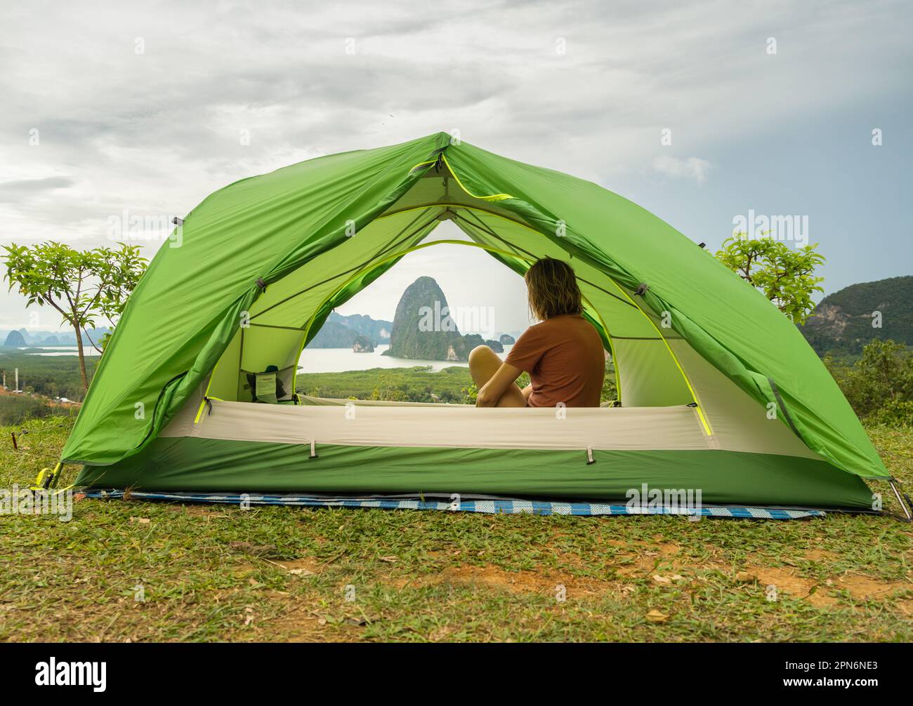 Donna viaggiatrice seduta all'interno di una tenda ammirando il paesaggio della baia di Phang Nga Foto Stock