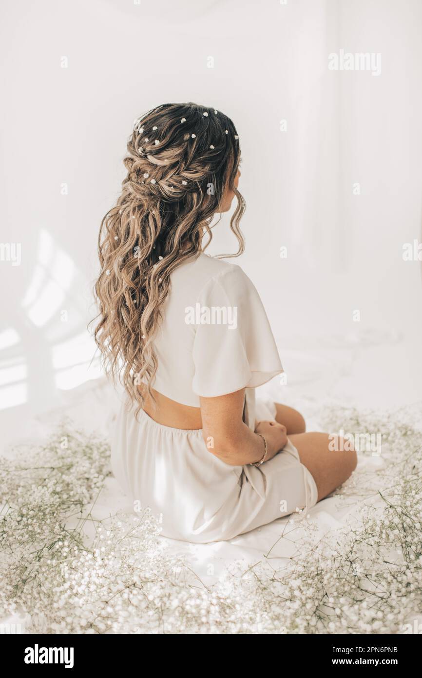 Giovane donna con fiori in capelli seduti con fiori di respiro del bambino Foto Stock