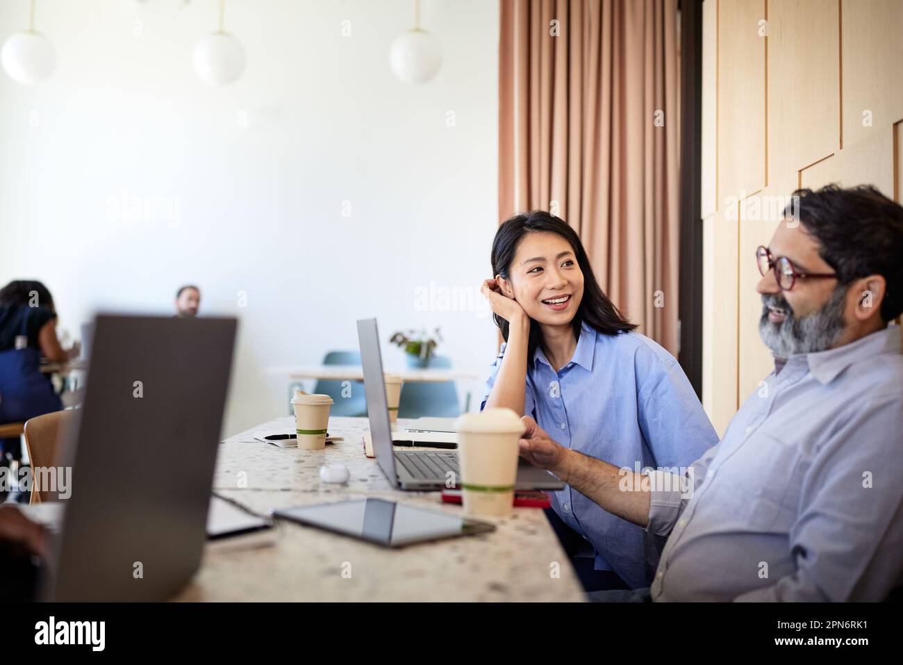 donna d'affari che parla con un collega con un computer portatile in un bar Foto Stock