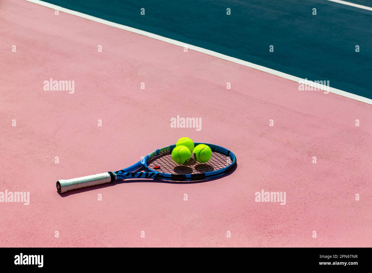 Racchetta da tennis e palle da tennis sui campi da tennis rosa e blu Foto Stock