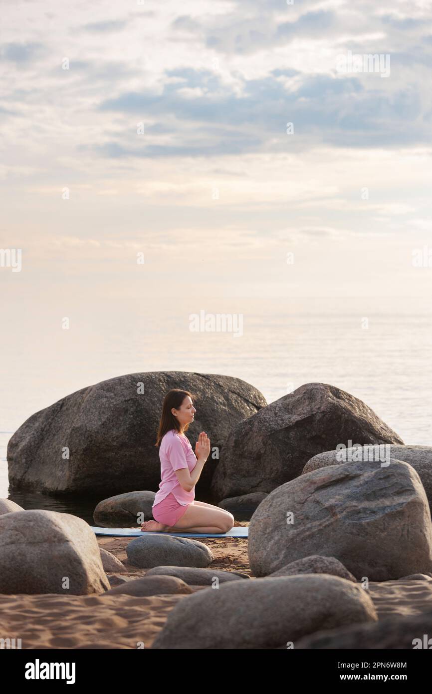 Vista laterale di una donna che fa yoga con un gesto Namaste . Foto Stock