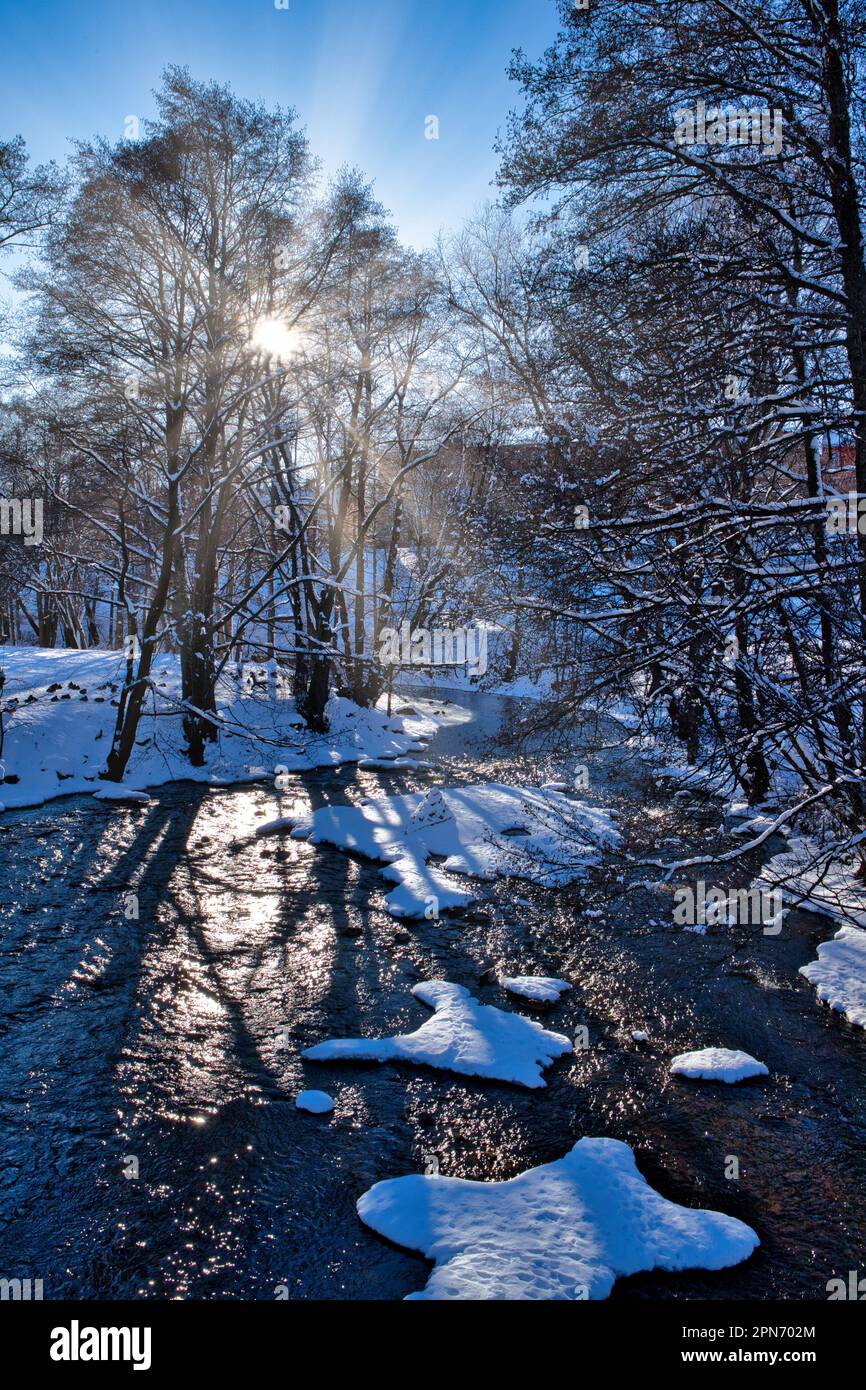 Bella scena invernale dopo la neve con il sole scoppiare attraverso gli alberi al fiume Akerselva, Oslo, Norvegia Foto Stock