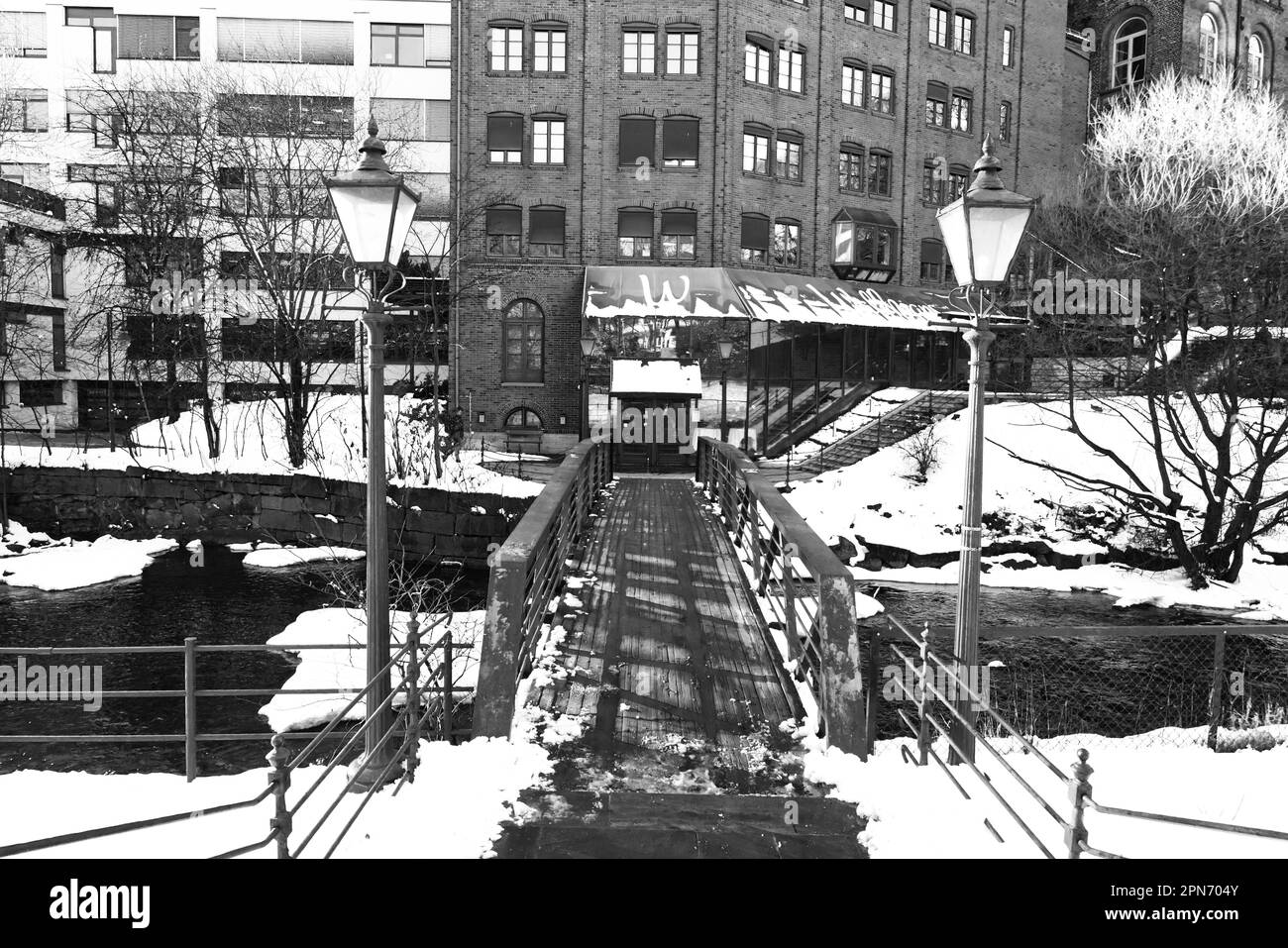 Ingresso attraverso il ponte al vecchio edificio del mulino che ospita il night club Wallmans sul fiume Akerselva, Oslo, Norvegia in inverno dopo la neve Foto Stock