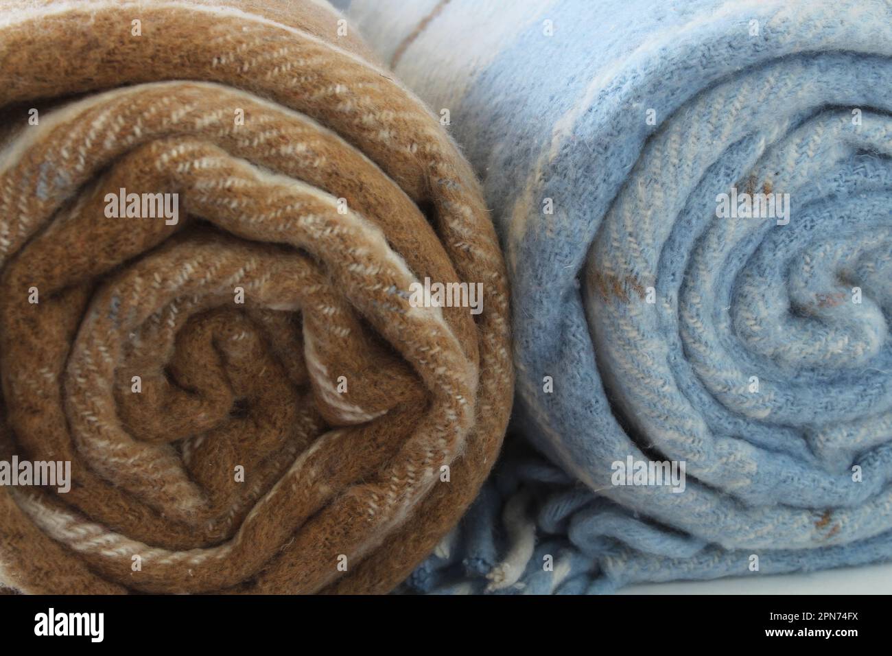 Coperta in lana a quadri isolata su fondo bianco. Coperta arrotolata beige-marrone e bianco-blu. Primo piano. Foto Stock