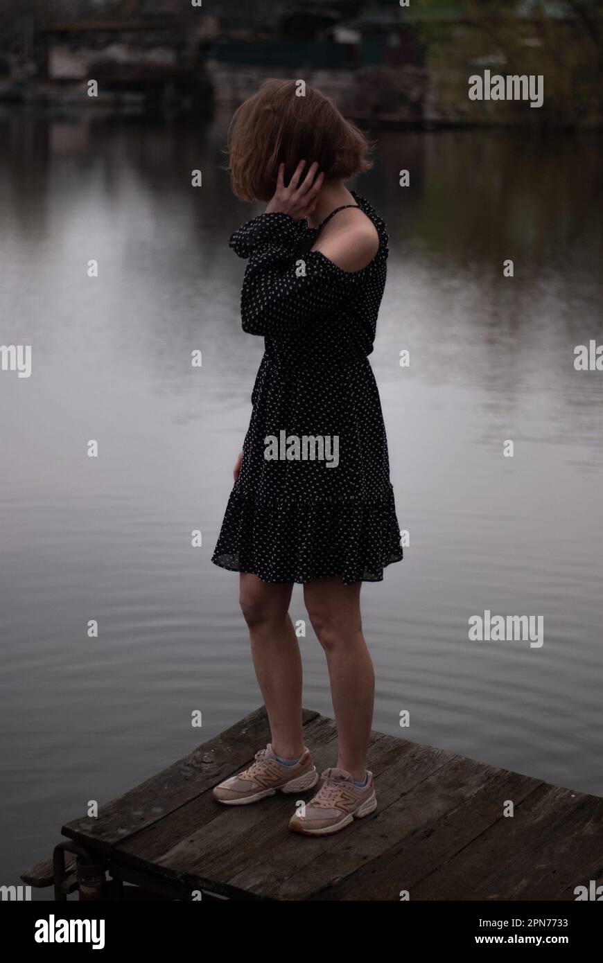Vista su una ragazza in vestito vicino al lago Foto Stock