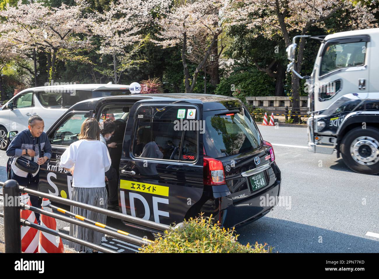 Aprile 2023, Toyota JPN ibrido nero taxi ferma a Tokyo per prendere una signora tariffa e porte aperte, Giappone, Asia Foto Stock