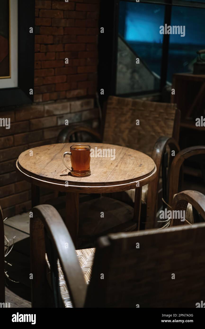 Ritratto o scatto verticale di un bicchiere di tè sul tavolo tradizionale e all'interno con sfocato primo piano e sfondo Foto Stock