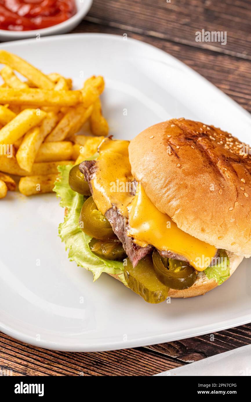 Delizioso hamburger di manzo con patatine fritte, anelli di cipolla e salse Foto Stock