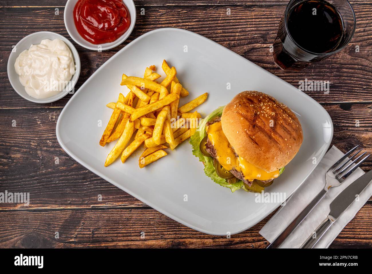 Delizioso hamburger di manzo con patatine fritte, anelli di cipolla e salse Foto Stock