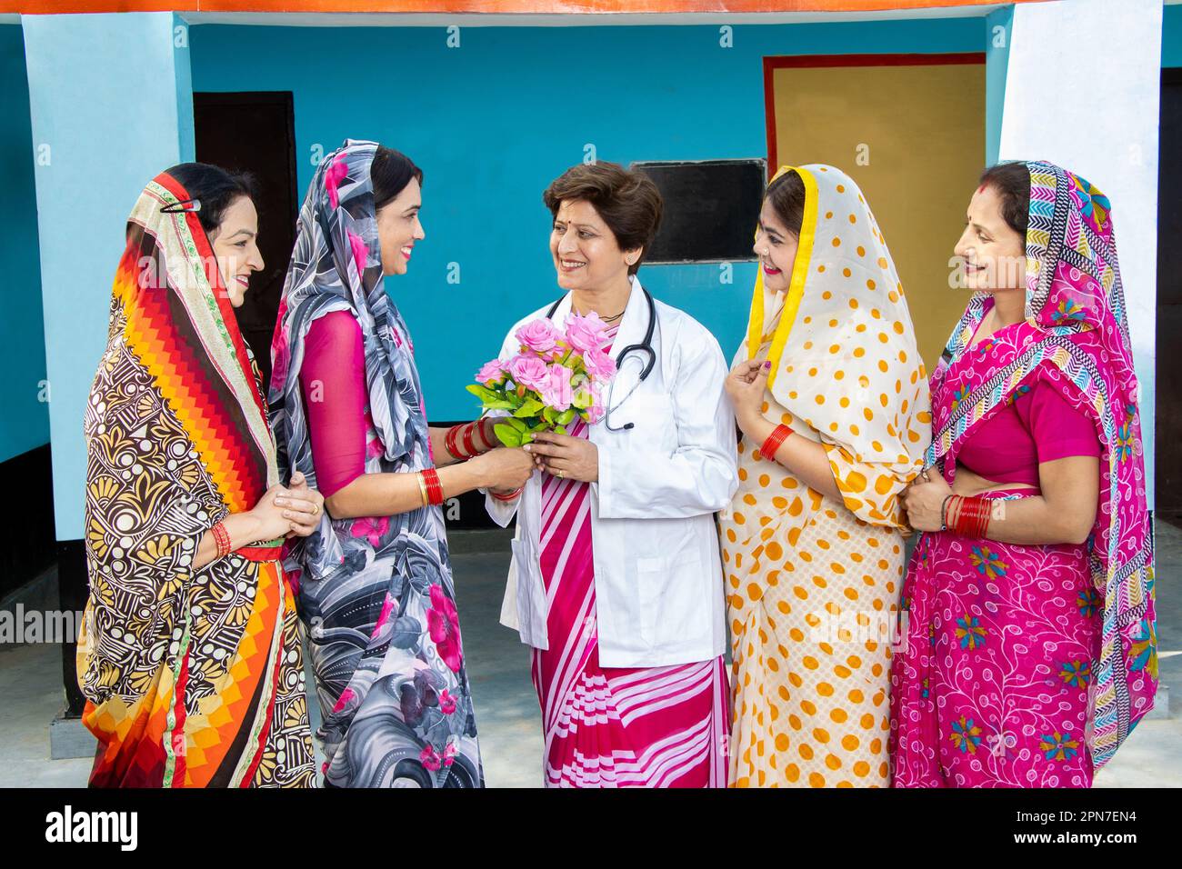 Gruppo di donne indiane tradizionali che indossano sari ringraziando e salutando medico dando bouquet di fiori, concetto di empowerment donna Foto Stock