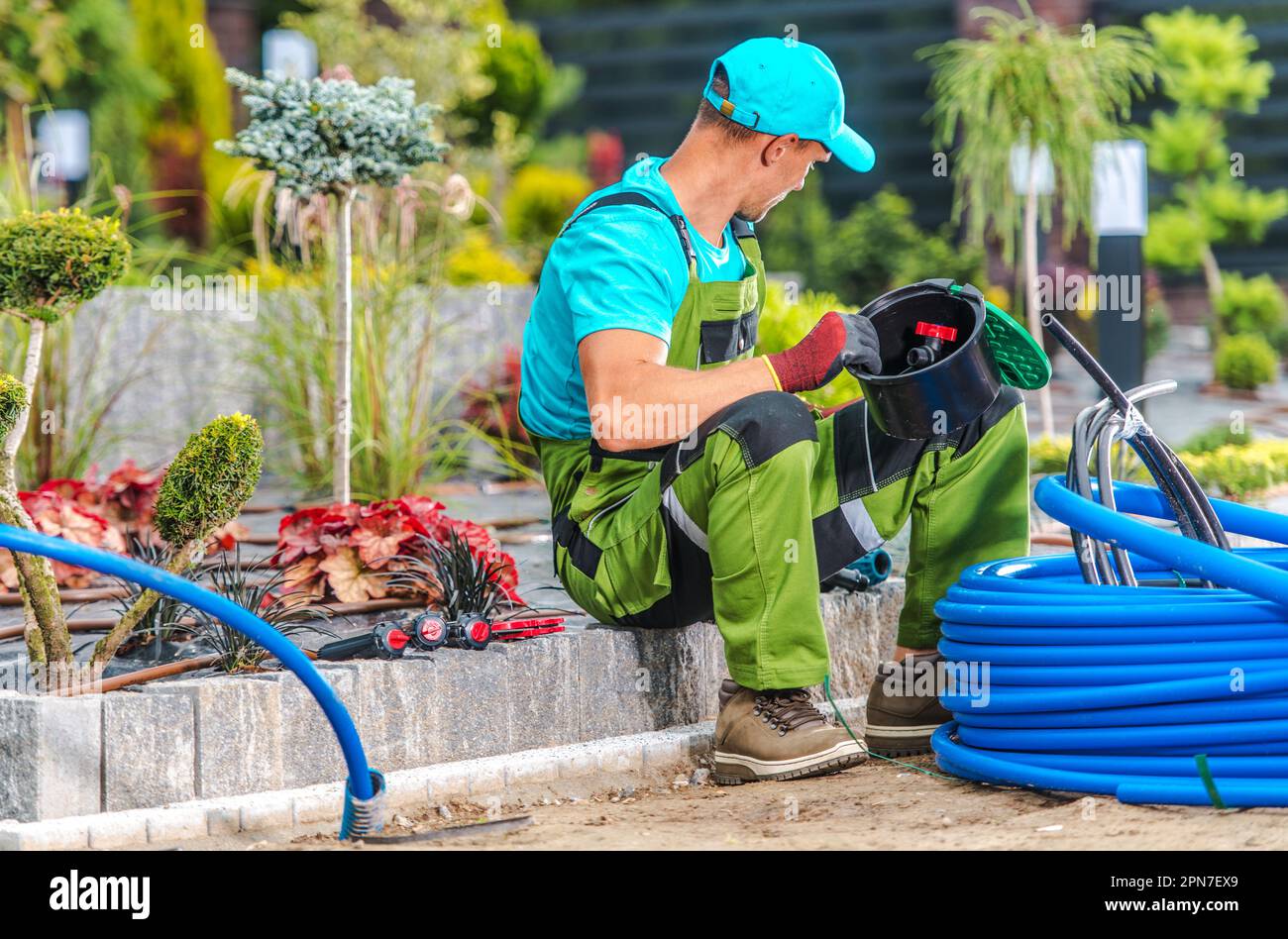 Giardiniere professionista prepararsi a installare sprinkler nel giardino per garantire un'irrigazione corretta. Foto Stock