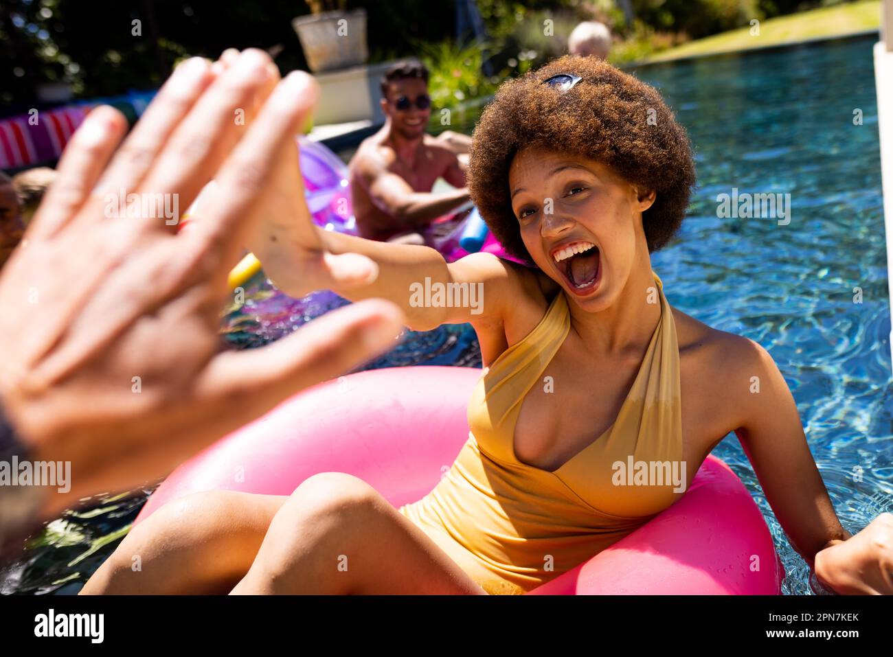 Felice gruppo di amici diversi che hanno partito in piscina, utilizzando anelli da nuoto in piscina in giardino Foto Stock Felice gruppo di amici diversi che hanno partito in piscina, utilizzando anelli da nuoto in piscina in giardino Foto Stock