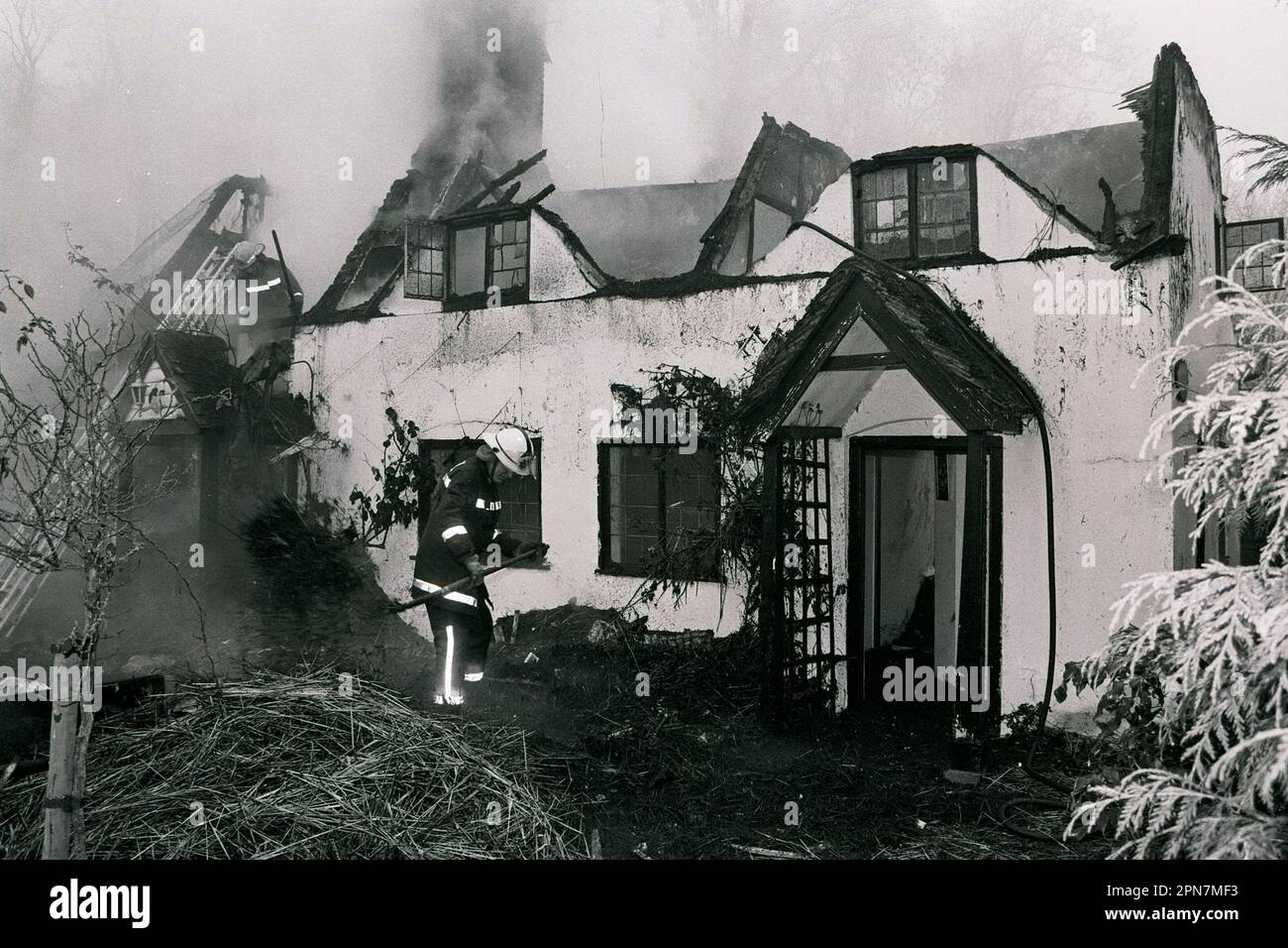 I vigili del fuoco inumidiscono un incendio in un cottage remoto vicino a Salisbury 1990. Foto Stock