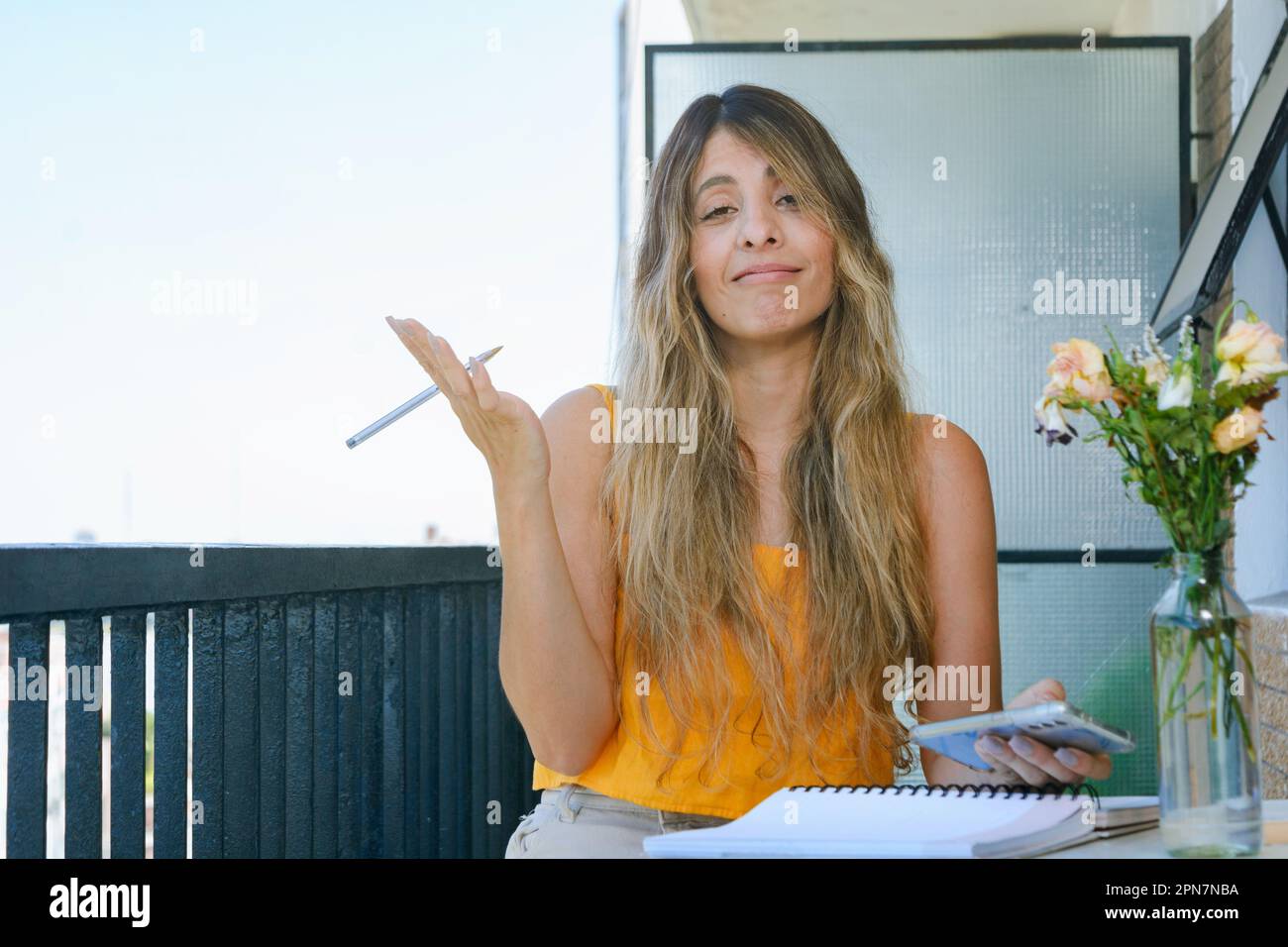 giovane imprenditore donna seduta sul balcone guardando la fotocamera facendo rassegnazione gesto con le mani e il viso Foto Stock
