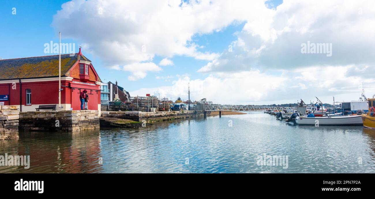 Una vista delle barche ormeggiate a Poole Harbour in Dorset, Regno Unito con la vecchia casa rossa di scialuppa di salvataggio RNLI sulla sinistra. Foto Stock