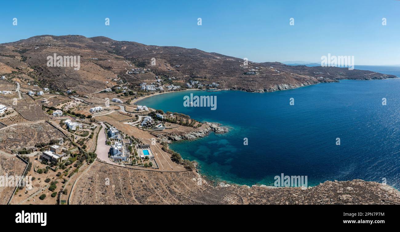 Isola di Tinos, Cicladi Grecia. Vista aerea del villaggio di Agios Romanos, edificio, terra rocciosa, baia, mare calmo, cielo blu. Destinazione estiva Foto Stock