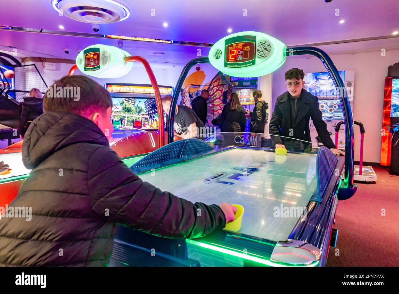 Fratelli che giocano una partita di hockey aereo in una sala giochi a Bournemouth, Dorset, Regno Unito Foto Stock