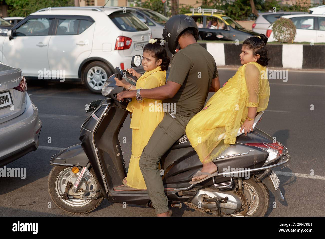 Un padre a Mumbai, in India, prende le sue due figlie vestite in modo identico per un giro sul suo scooter a motore Foto Stock