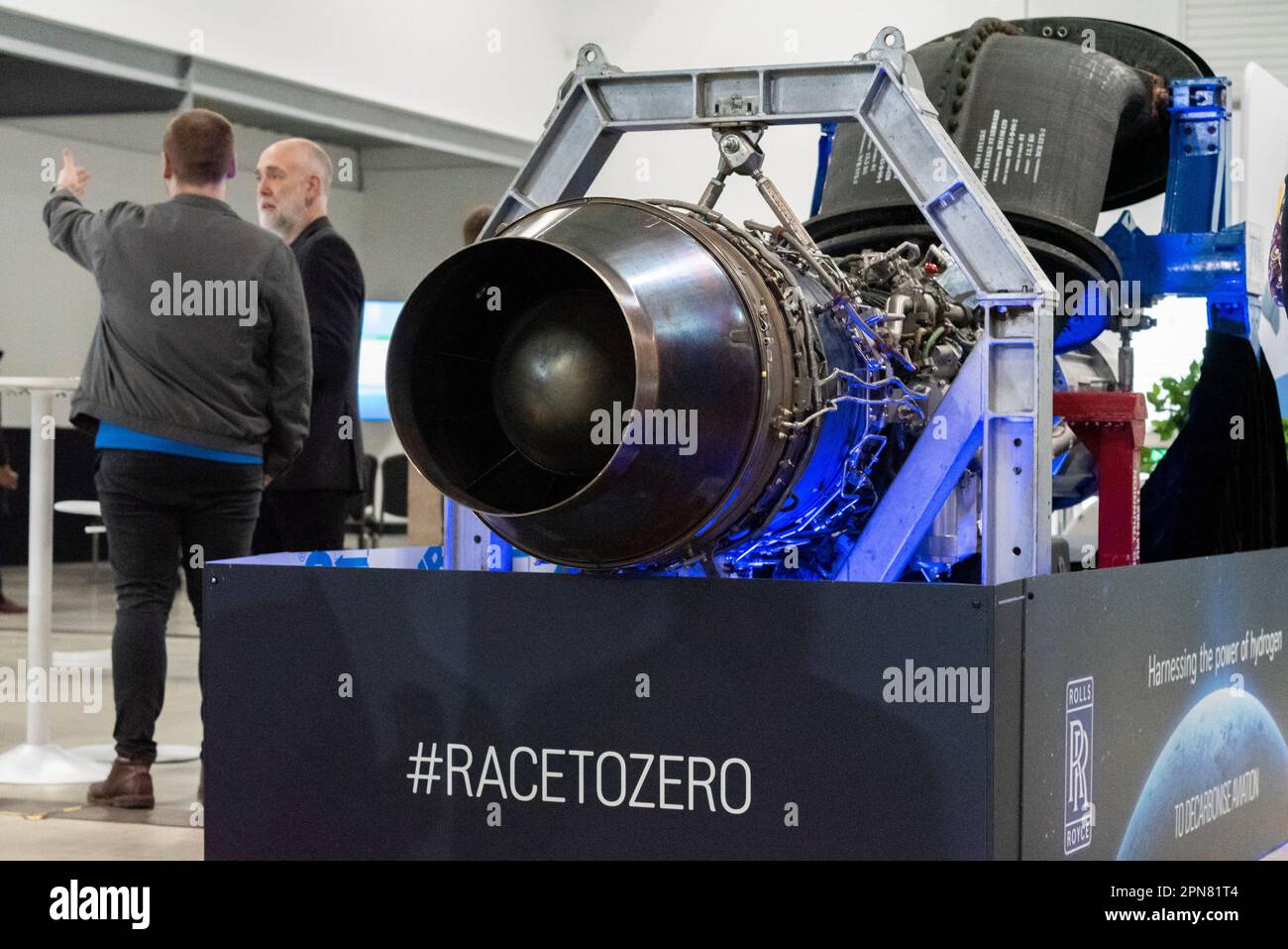 Aeroporto di Farnborough, Hampshire, Regno Unito. 17th Apr, 2023. I leader e le aziende del settore aerospaziale si sono riuniti al Farnborough International Exhibition & Conference Centre per concentrarsi sull'obiettivo di accelerare i progressi globali verso un'aviazione netta pari a zero entro il 2050. Gli altoparlanti e i display Keynote hanno evidenziato gli sviluppi nei motori elettrici e nei carburanti alternativi per sostituire i motori aerodinamici tradizionali, nonché i cambiamenti operativi per ridurre l'impatto sul clima. Un motore aero Rolls-Royce AE 2100-A convertito da cui verrà sviluppato il primo motore a funzionare esclusivamente a idrogeno. Slogan Race to zero Foto Stock