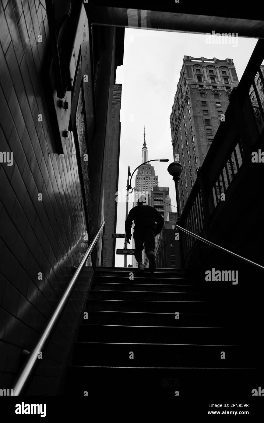 L'uomo che corre lungo i gradini della metropolitana verso l'Empire state Building a New York City Foto Stock
