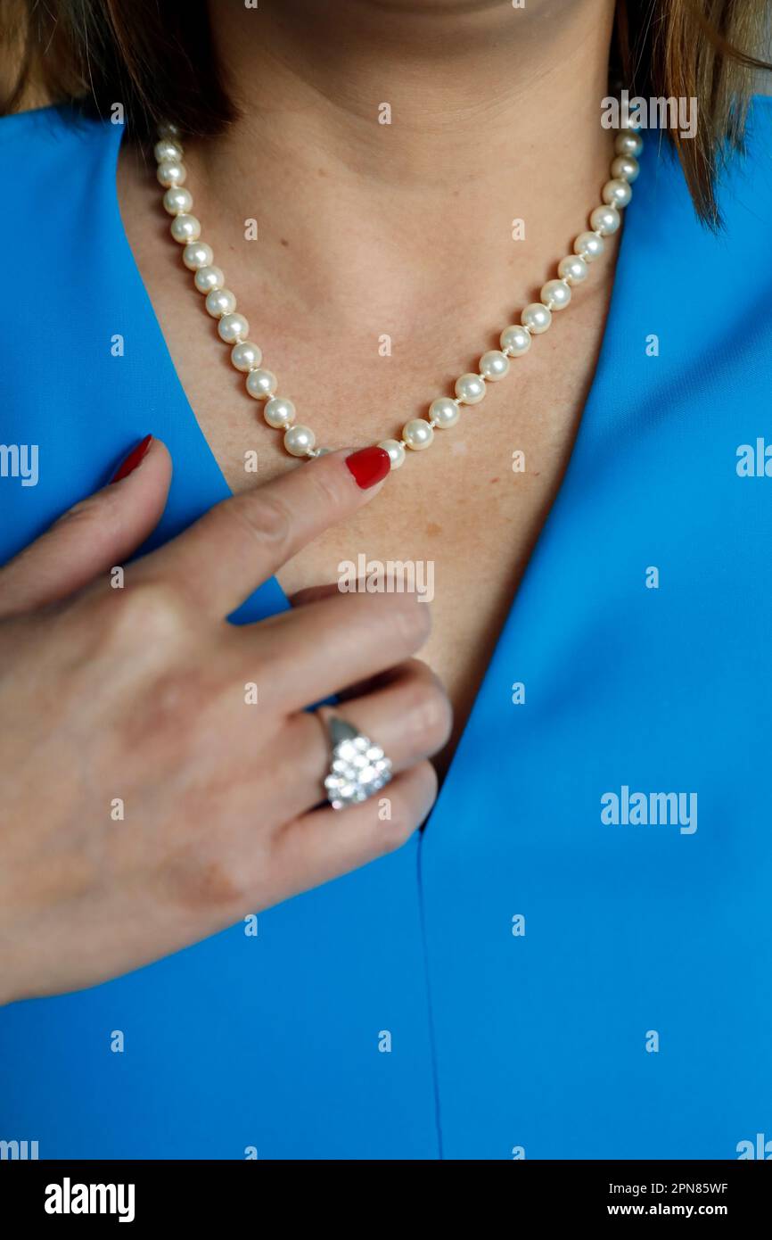 Donna che indossa un abito blu e collana in perla. Foto Stock