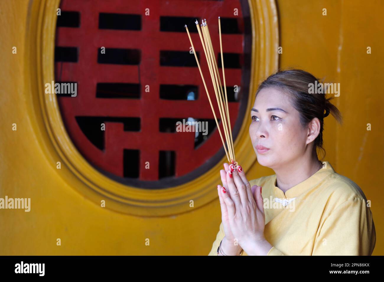 Tempio di Rong Thanh. Donna buddista che prega con bastoni d'incenso. Concetto di fede. Tan Chau. Vietnam. Foto Stock