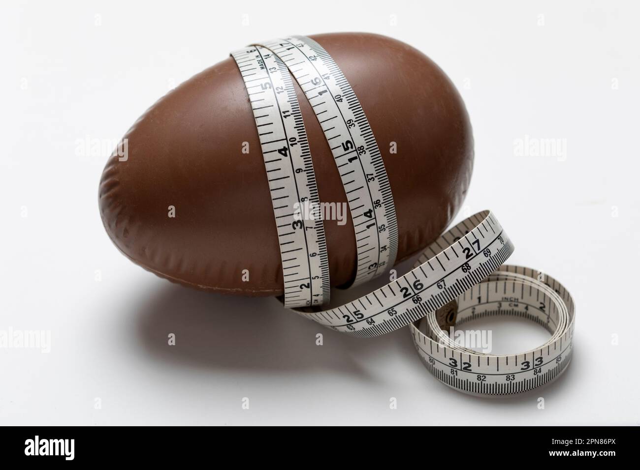 Uovo di Pasqua al cioccolato con metro a nastro in pollici e cm Foto Stock